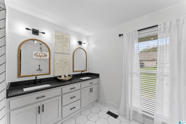bathroom featuring baseboards, double vanity, a sink, and tile patterned floors