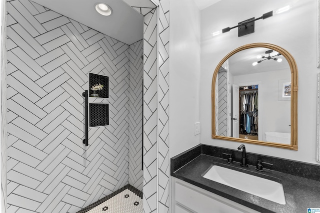 full bathroom with tiled shower and vanity