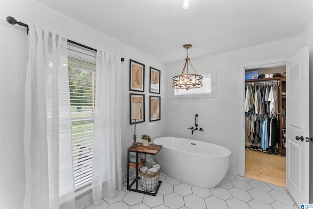 bathroom featuring tile patterned floors, a freestanding bath, and a notable chandelier