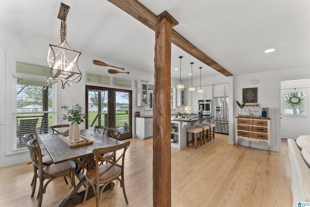 dining space featuring light wood-style flooring, beamed ceiling, recessed lighting, an inviting chandelier, and french doors