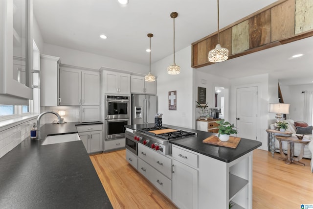kitchen featuring dark countertops, a sink, stainless steel appliances, and open shelves