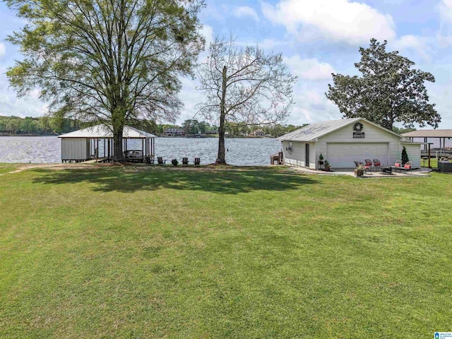 view of yard with a gazebo, a water view, a garage, and an outbuilding