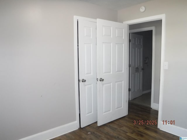 unfurnished bedroom with dark wood-style floors and baseboards