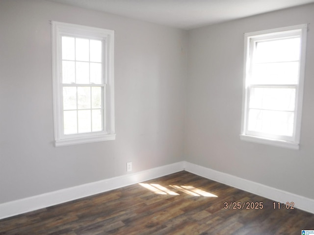 spare room with baseboards and dark wood finished floors