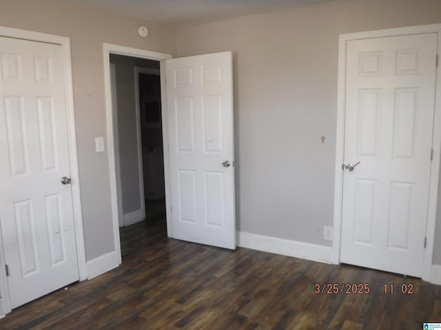 unfurnished bedroom with baseboards and dark wood-style flooring