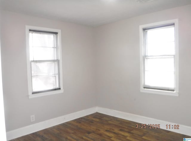spare room with baseboards and dark wood-style flooring