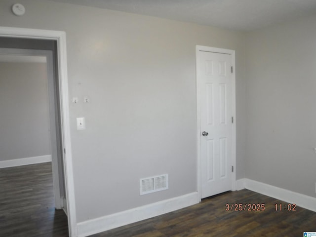 empty room with baseboards, visible vents, and dark wood-style flooring