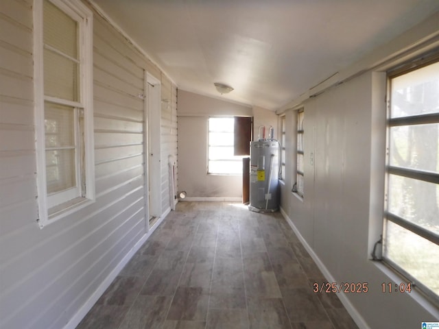 hall featuring baseboards, electric water heater, wood finished floors, and vaulted ceiling