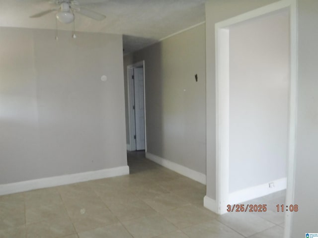 unfurnished room with baseboards, light tile patterned floors, and a ceiling fan