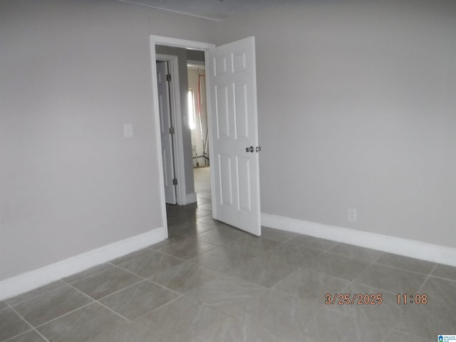 unfurnished room featuring baseboards and tile patterned flooring