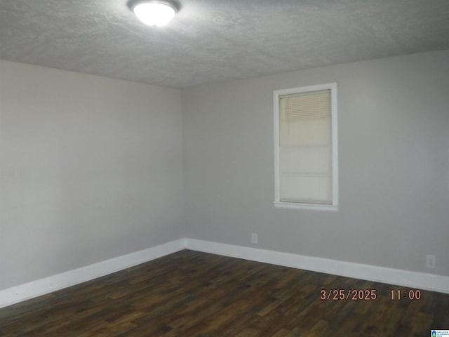 spare room with baseboards, dark wood-style flooring, and a textured ceiling