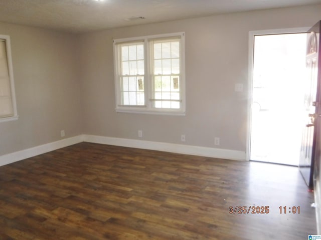 spare room with baseboards and wood finished floors