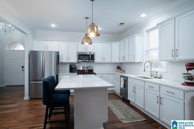 1595 Creekstone Cir, Birmingham, AL 35243 - kitchen featuring appliances with stainless steel finishes, a kitchen island, white cabinets, decorative backsplash, and ornamental molding