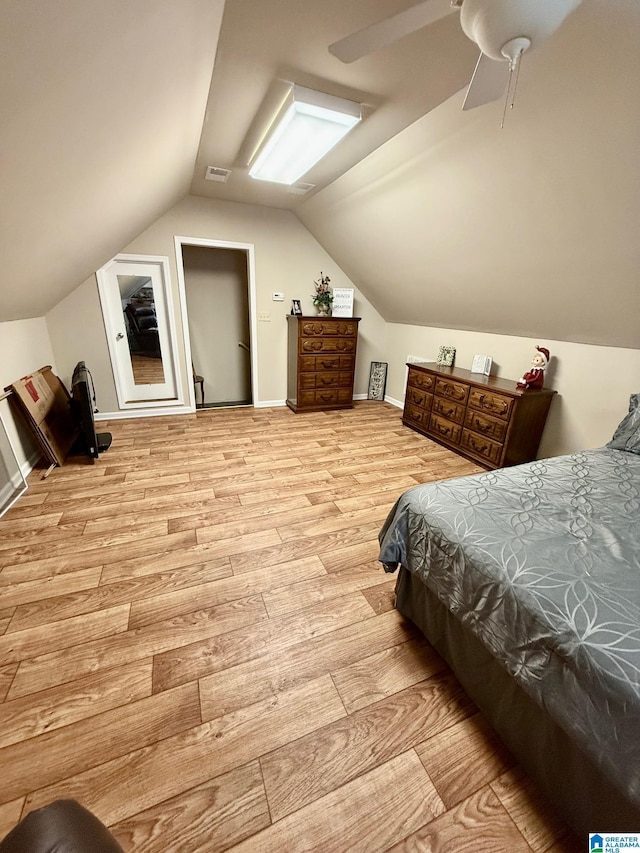 bedroom featuring light wood-style flooring, vaulted ceiling, baseboards, visible vents, and a ceiling fan