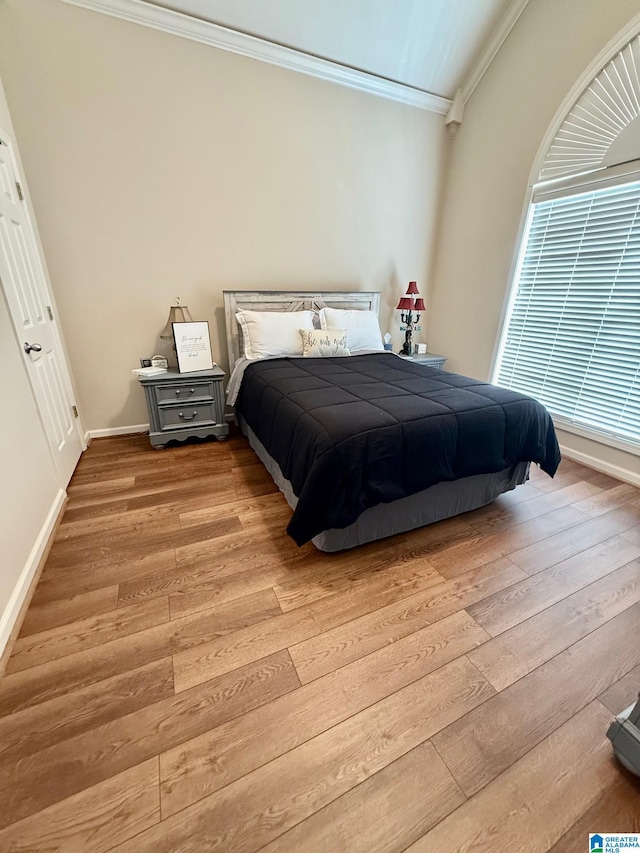 bedroom featuring baseboards, light wood-style floors, and ornamental molding