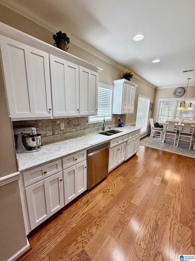 kitchen with ornamental molding, decorative backsplash, stainless steel dishwasher, a sink, and light wood finished floors