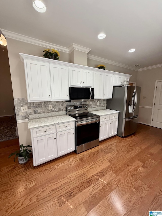 kitchen with white cabinetry, stainless steel appliances, ornamental molding, backsplash, and light wood-style flooring