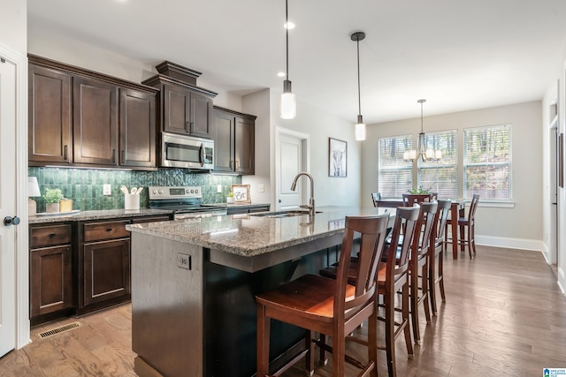 13147 Allison Dr, Lake View, AL 35111 - kitchen featuring light stone counters, dark brown cabinets, stainless steel appliances, light wood finished floors, and a sink