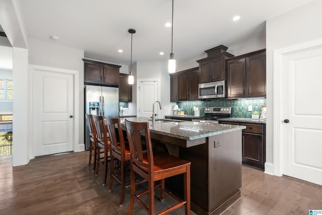 13147 Allison Dr, Lake View, AL 35111 - kitchen featuring a sink, a kitchen island with sink, dark brown cabinets, stainless steel appliances, and a breakfast bar area