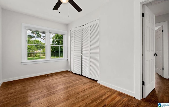 unfurnished bedroom with visible vents, a closet, baseboards, ceiling fan, and wood finished floors