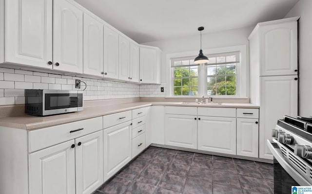 kitchen featuring white cabinets, decorative light fixtures, a sink, stainless steel appliances, and decorative backsplash