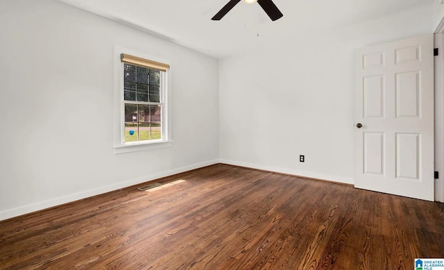 spare room with dark wood-type flooring, baseboards, and a ceiling fan