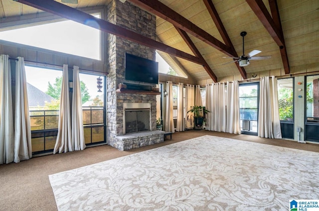 living room featuring wood ceiling, carpet flooring, ceiling fan, beam ceiling, and a stone fireplace