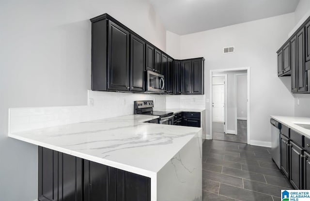 kitchen featuring stainless steel appliances, decorative backsplash, visible vents, a peninsula, and dark cabinets