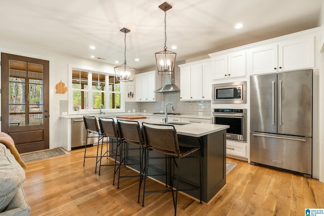 kitchen featuring white cabinets, light countertops, light wood finished floors, stainless steel appliances, and backsplash