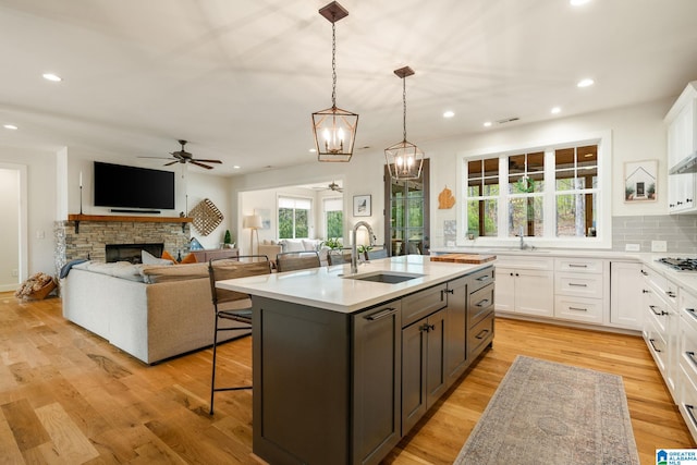 kitchen with a breakfast bar area, ceiling fan with notable chandelier, a sink, and white cabinets