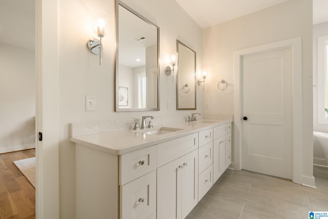 bathroom with double vanity, visible vents, a sink, and wood finished floors