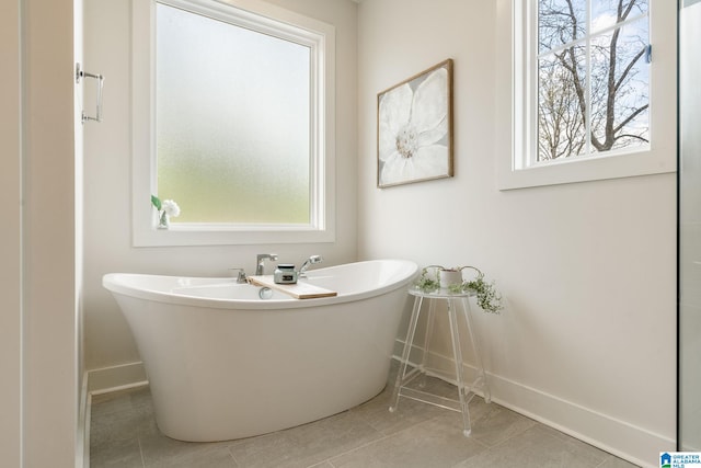 bathroom with a wealth of natural light, a freestanding bath, and tile patterned flooring