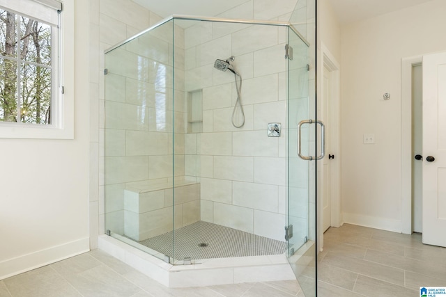 bathroom featuring tile patterned flooring, baseboards, and a stall shower