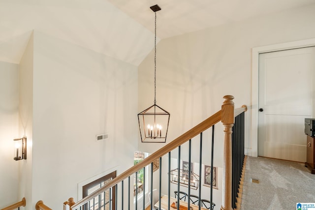 stairway with visible vents, high vaulted ceiling, carpet flooring, and an inviting chandelier