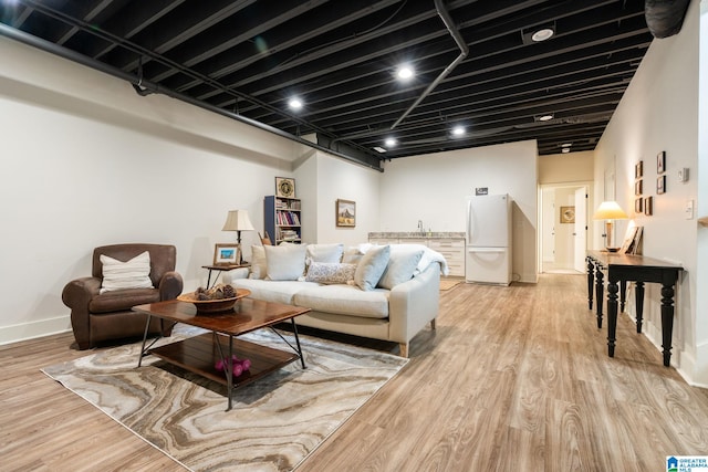 living area with light wood-style flooring, bar area, and baseboards