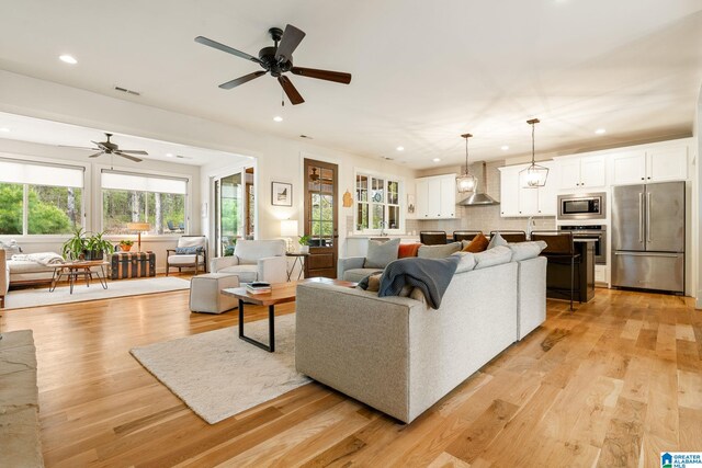 living area featuring visible vents, ceiling fan, and light wood-style floors