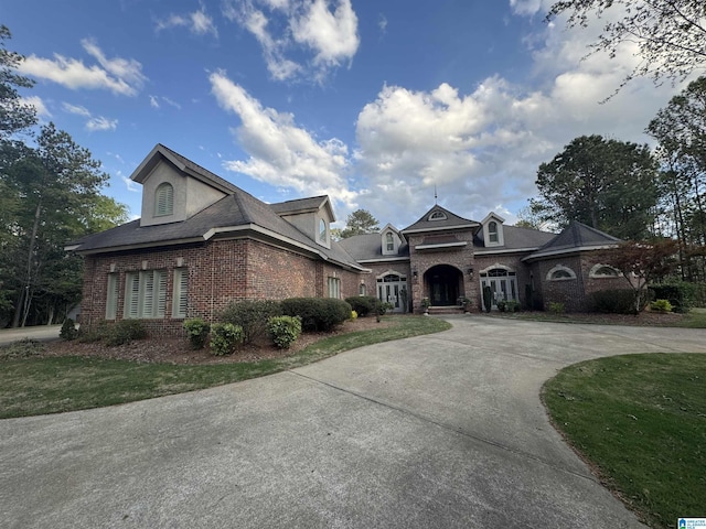 view of front of property with brick siding and curved driveway