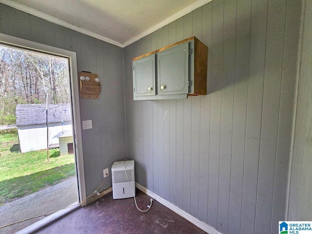 empty room with wooden walls, baseboards, and crown molding