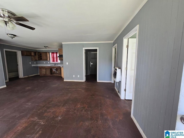 unfurnished living room featuring ceiling fan, ornamental molding, a sink, baseboards, and heating unit