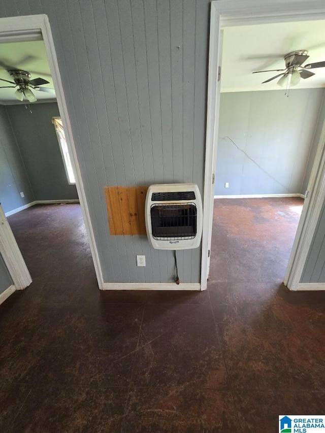 room details with wood walls, baseboards, a ceiling fan, and heating unit