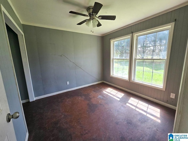 interior space featuring ornamental molding, baseboards, a ceiling fan, and wood walls