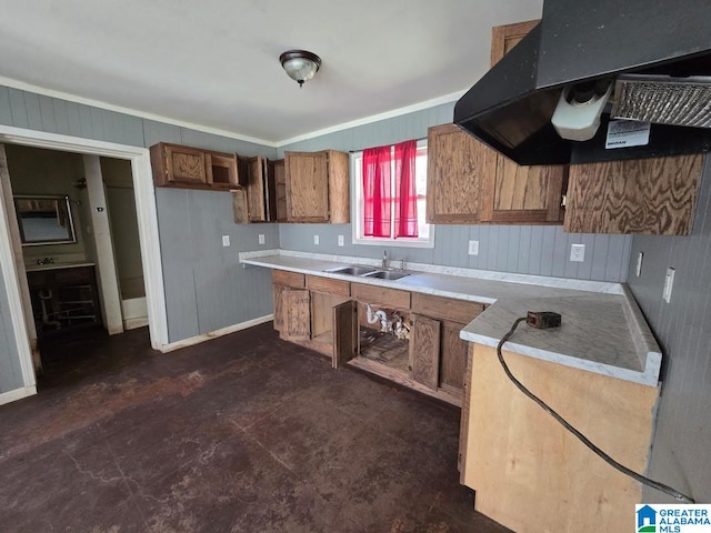 kitchen with wooden walls, light countertops, exhaust hood, brown cabinetry, and a sink