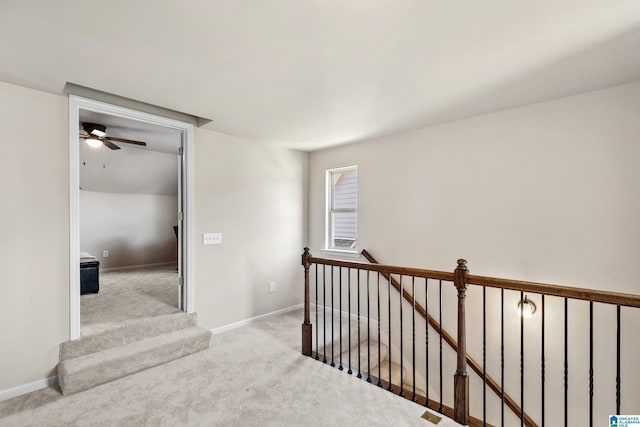 hall featuring an upstairs landing, baseboards, and carpet floors