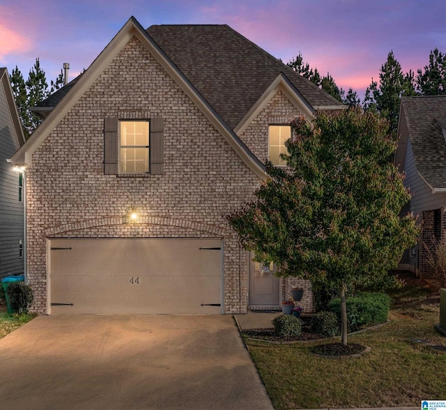 traditional-style home with brick siding, driveway, and an attached garage