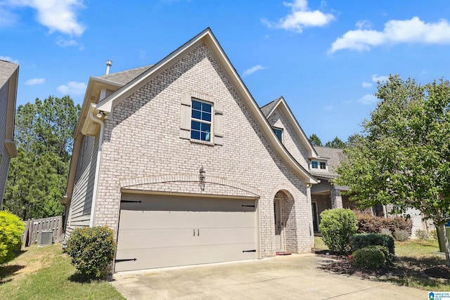 view of front of property featuring brick siding, driveway, and fence