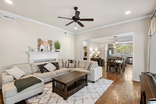 living room with visible vents, ornamental molding, ceiling fan, recessed lighting, and wood finished floors