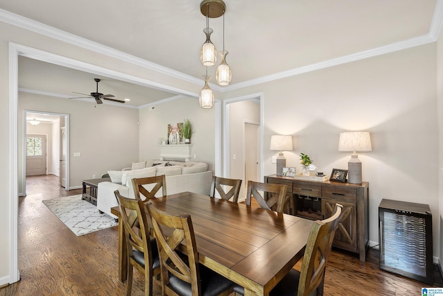 dining area featuring dark wood-style flooring, baseboards, a ceiling fan, and crown molding