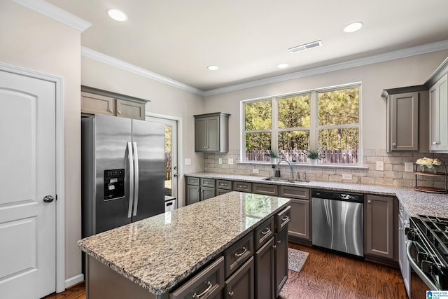 kitchen with tasteful backsplash, light stone countertops, dark wood-type flooring, appliances with stainless steel finishes, and a sink