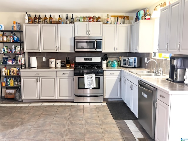 kitchen with a sink, light countertops, decorative backsplash, and stainless steel appliances