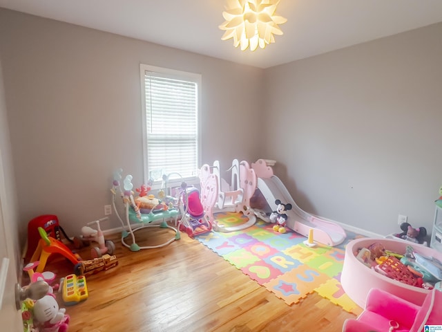 playroom with baseboards, an inviting chandelier, and wood finished floors
